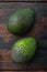 Whole pair of green avocado, on old wooden table, top view or flat lay