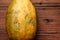 whole papaya on a wooden background. An imperfect-looking fruit with an uneven surface