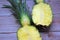 Whole pineapple cut in half, two pieces of pineapple halves, pineapple fruit on wooden background, yellow fruit