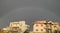 A whole rainbow appearing over beautiful houses after rain