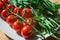 Whole red tomato cherry and fresh ruby leaves composition on a white plate on the wooden table