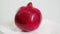 Whole ripe red pomegranate fruit on white plate rotates
