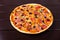 A whole rustic pizza capriciosa with sausages, bacon, pepper and mushrooms