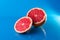 Whole and slicend on half grapefruit on a blue background, horizontal shot