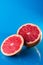 Whole and slicend on half grapefruit on a blue background, vertical shot