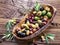 Whole table olives in the wooden bowl.