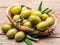 Whole table olives in the wooden bowl on the table.