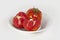 Whole tomato with green tail and a half cut tomato in a white vintage porcelain bowl.