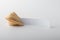 A whole traditional Chinese fortune cookie with a blank note for text, on a light background. Wish fulfillment concept.