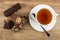 Whole wafer, pieces of wafer in chocolate, cup of tea, spoon on saucer on table. Top view