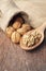 Whole walnuts in sackcloth bag and walnut kernels on wooden spoon