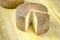 Whole wheel of sheep milk cheese over yellow wood