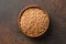 Wholegrain spelt farro in wooden bowl on brown background. Top view