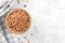 Wholegrain uncooked raw spelt farro in ceramic bowl with napkin on grey table