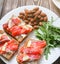 Wholemeal bread with salmon on white plate. Arugula and almond with lemon. Healthy sandwiches. Omega-3 for snack. Proper nutrition