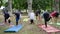 Wholesome women and men doing exercises, people practice yoga, fitness warm-up in outdoor, yoga class outdoors