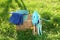 Wicker basket with bucket, gloves and gardening tools on grass outdoors