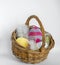 Wicker basket filled with knitted easter eggs in front of a light background as a basis for an Easter card