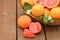 Wicker basket with fresh grapefruits and green leaves on wooden table