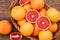 Wicker basket with fresh grapefruits on wooden table, flat lay