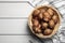 Wicker basket with fresh Jerusalem artichokes on white wooden table, top view. Space for text