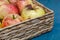 Wicker basket with fresh organic ugly apples on the blue background. close up.