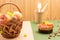 Wicker basket with fruits and nuts on brown. Nuts, candied fruits and disposable tableware on green