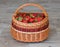 Wicker basket full of ripe garden strawberries on grey / brown wooden tiles. Fresh home grown strawberry in basket.