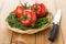 Wicker basket with greens and tomatoes and kitchen knife