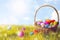 Wicker basket with painted Easter eggs in sunlit green grass, space for text