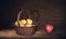 Wicker Basket with pears and one apple on table, dark painting background.