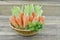 Wicker basket with ripe carrots on wooden