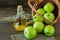 Wicker basket with ripe green apples and bottle of aplle vinegar on wooden background