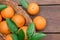 Wicker basket, ripe juicy oranges and green leaves on wooden table, flat lay