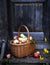 A wicker basket with rosy apples on a wooden porch surrounded by flowers.