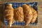 Wicker basket with traditional french croissants and chocolate pies on checkered napkin