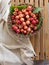 Wicker bowl with cherries. Ripe cherries with green leaves. A bowl stands on a wooden table on a linen cloth