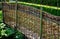 Wicker braided wall of willow red rods in the garden of medieval style with supporting poles dividing the flowerbeds of the herb