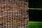 wicker braided wall of willow red rods in the garden of medieval style with supporting poles dividing the flowerbeds of the herb