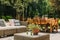 Wicker coffee table in front of Dining table covered with orange tablecloth standing on wooden terrace in green