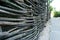 Wicker fence of vines, branches, hedge, against the backdrop of footpaths of stone and green bushes