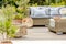 Wicker garden furniture with grey pillows in beautiful backyard