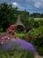 A wicker gazebo, lush lavender field, climbing pink roses in the garden.