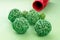 Wicker green balls on a green surface. red container in the background