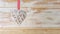 Wicker heart made of straw hanging on ribbon on wooden background. Valentine day or love concept. Copy space
