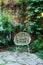 Wicker rattan chair outdoors in garden, on the background brick wall with curly wild grapes. Wooden armchair standing on backyard