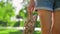 Wicker summer sandals in the hands of young girl in denim shorts and white linen shirt in park at sunset. Concept of