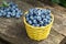 Wicker yellow basket with blueberries on a wooden table in the garden,