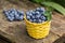 Wicker yellow basket with blueberries on a wooden table in the garden.