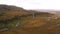 Wide aerial mountain landscape in Iceland, beautiful green plain and a small village near a waterfall. Drone shot of a big mountai